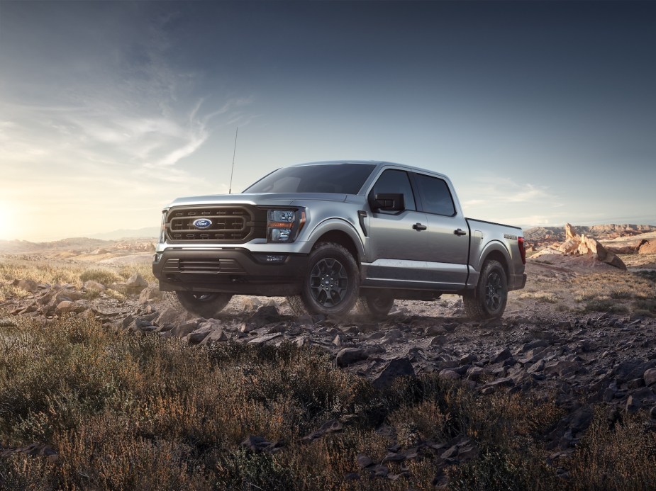 A full-size, light-duty, half-ton, Ford F-150 pickup truck parked on a rocky 4WD trail, a blue sky visible in the background.