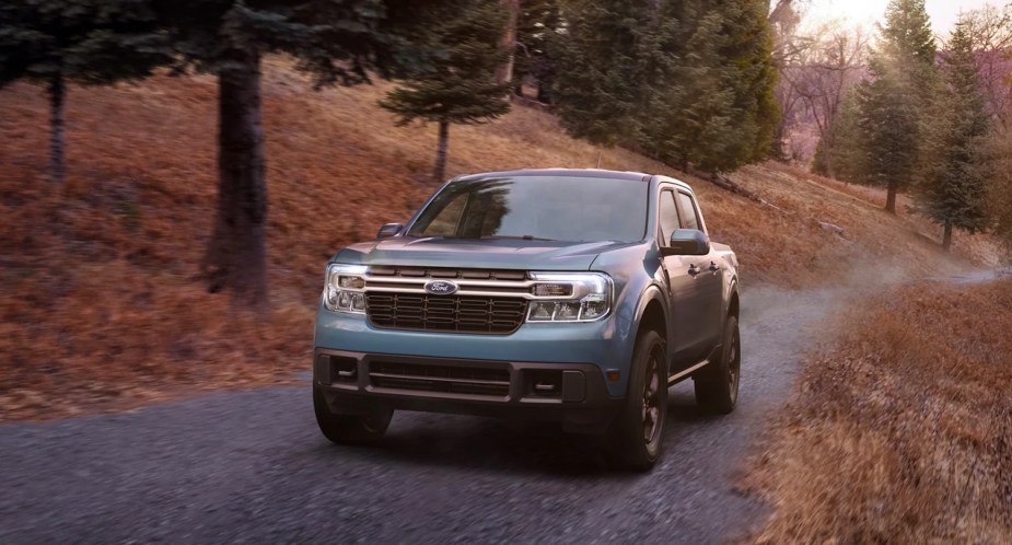 A blue 2023 Ford Maverick small pickup truck is driving off-road. 