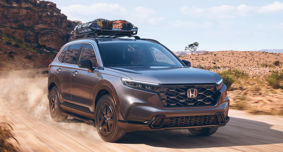 A gray 2023 Honda CR-V Hybrid small SUV is driving off-road. 