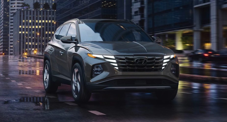 A black 2023 Hyundai Tucson Hybrid is driving on a wet road. 