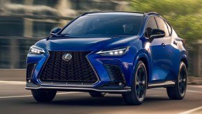 A blue Lexus NX 350h small luxury hybrid SUV is driving on the road.