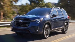 A blue 2023 Subaru Ascent midsize SUV is driving on the road.