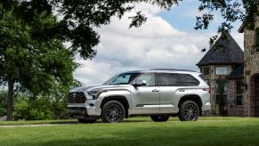 A 2023 Toyota Sequoia full-size SUV in Platinum Silver parked outside a luxury brick mansion