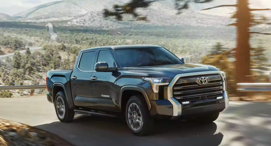 A black 2023 Toyota Tundra full-size pickup truck is driving on the road. 