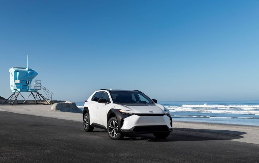 A 2023 Toyota bz4X compact electric SUV model in Wind Chill Pearl parked on a beach near a lifeguard station