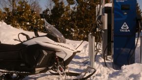 An electric snowmobile plugged into a charger.