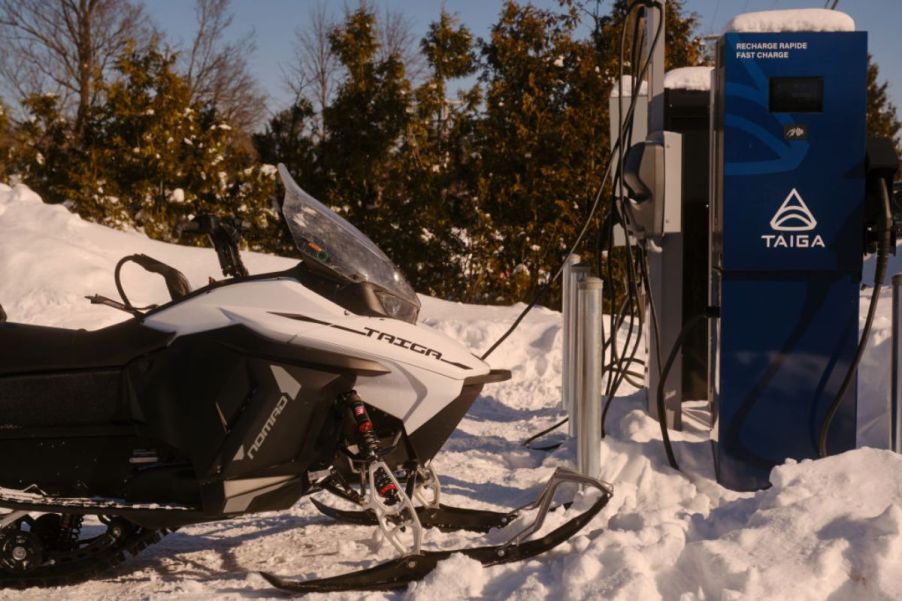 An electric snowmobile plugged into a charger.