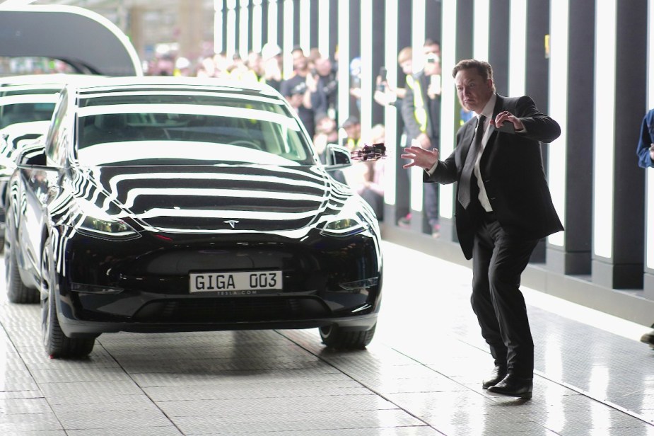 Elon Musk dancing by a black Tesla Model Y