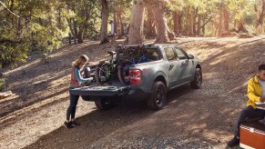 A blue 2023 Ford Maverick is parked outdoors with its truck bed open.