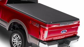 A red ford truck with a tonneau cover on the cargo bed. There are a few reasons to buy one.