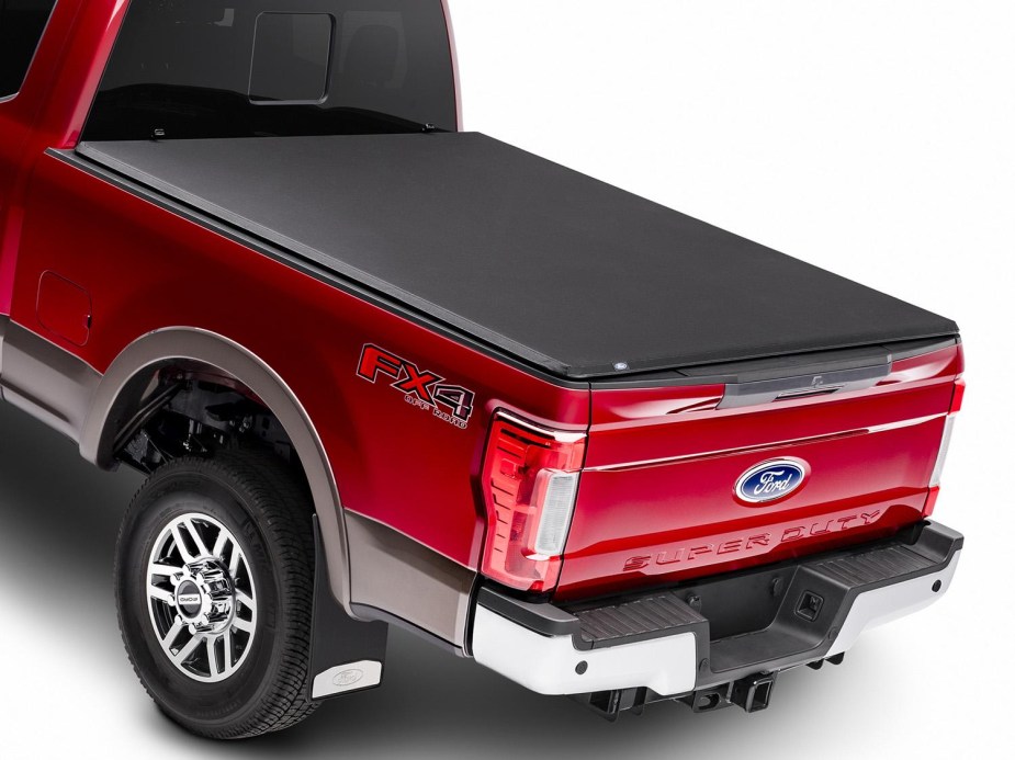 A red ford truck with a tonneau cover on the cargo bed. There are a few reasons to buy one.