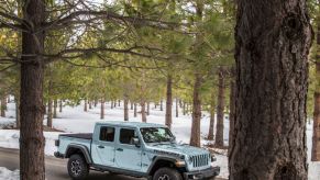 A 2023 Jeep Gladiator with early gray paint driving in the woods