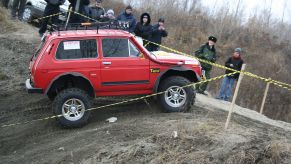 A red Lada Niva shows off its capability as a 4x4 SUV.