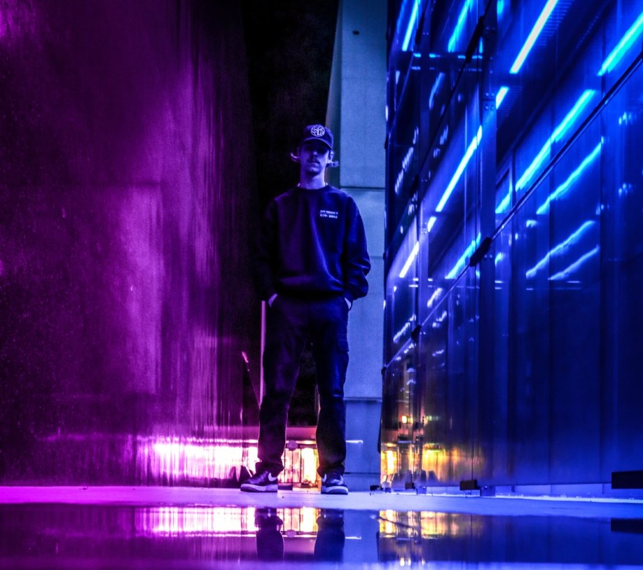 Man standing on street with purple lights, highlighting why street lights in cities are turning purple