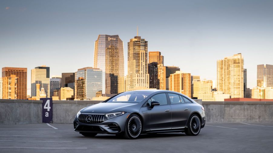 A dark gray Mercedes-Benz EQS all-electric luxury sedan model parked on the top floor of a parking garage