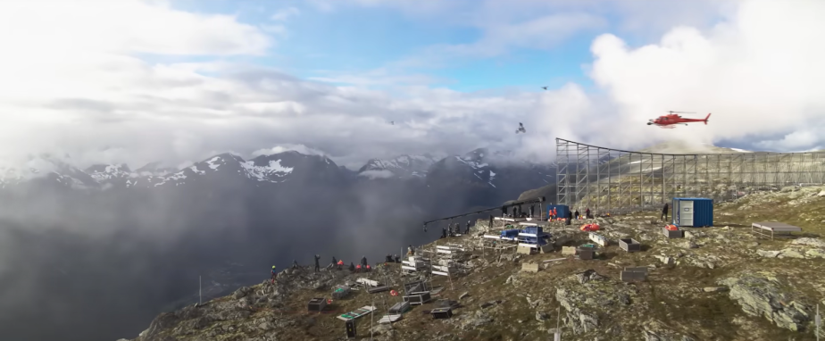 A set photo of Mission Impossible Dead Reckoning shows Tom Cruise jumping a motorcycle off of a cliff while a helicopter films.