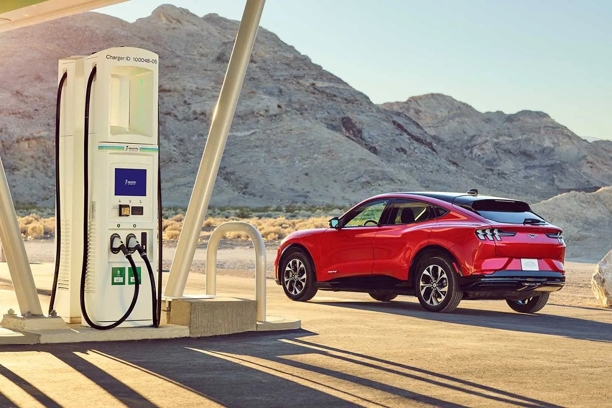 Red Ford Mustang Mach-E by charging station, highlighting how EVs reduce gas consumption in America less than expected