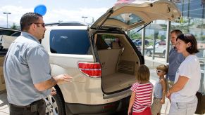 A family at a car dealership looking at a Saturn Outlook.