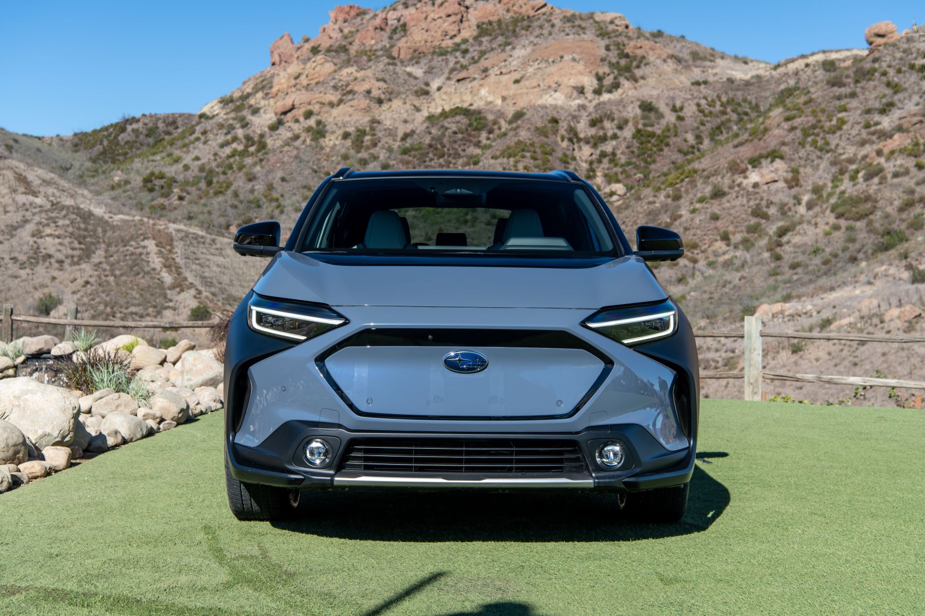 A light blue 2022 Subaru Solterra compact electric SUV model with an aesthetic fake grille panel