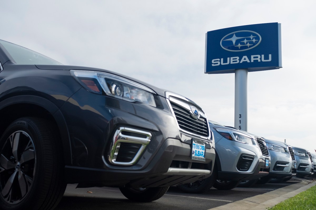 A row of Subarus under a dealership sign with the brand's name.