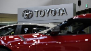 Toyota logo with red cars in front of it.