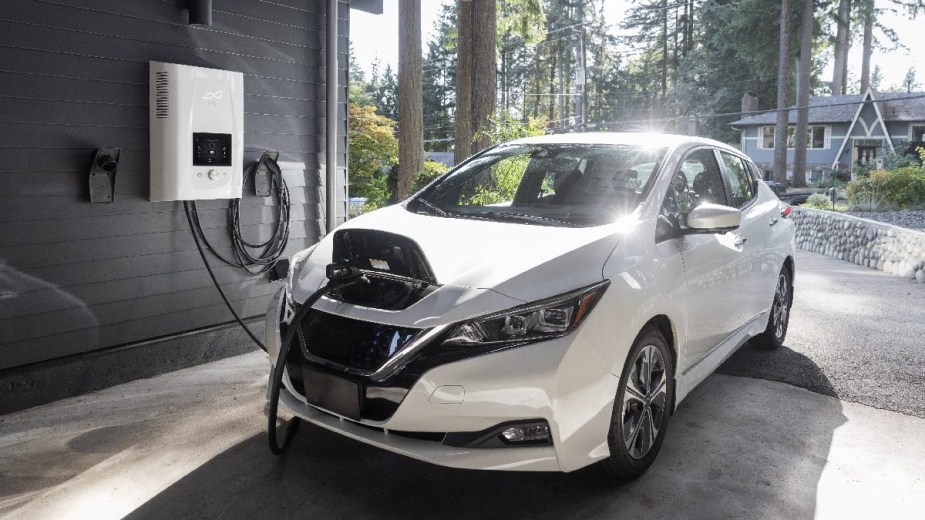 White Nissan LEAF charging, highlighting if it’s OK to leave an EV plugged in all the time or charge overnight