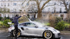 A car wash man cleans a luxury Porsche.