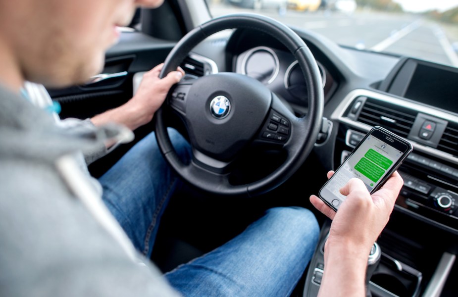 A man sits with his hand on a BMW steering wheel.