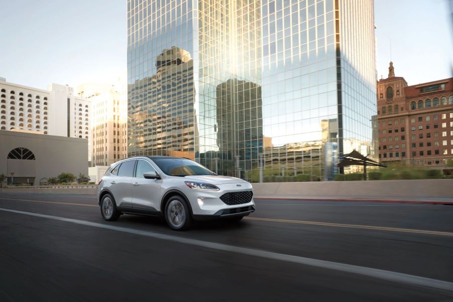 A white 2022 Ford Escape compact SUV driving past a reflective skyscraper