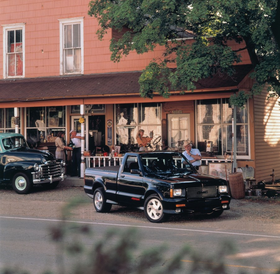 Black 1991 GMC Syclone pickup truck parked in front of an old building.