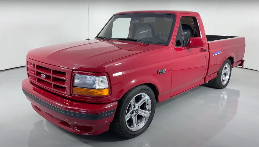 The grille of a Red Ford F-150 SVT Lightning muscle truck parked in a showroom, a white wall visible in the background.