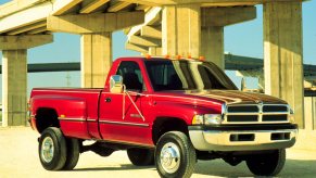 Red 2nd Gen Cummins Dodge Ram 3500 parked beneath a bridge for a publicity photo.