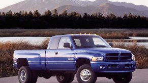 Blue 2001 Dodge Ram pickup truck with a 2nd Gen Cummins engine parked by a lake with mountains visible in the background.