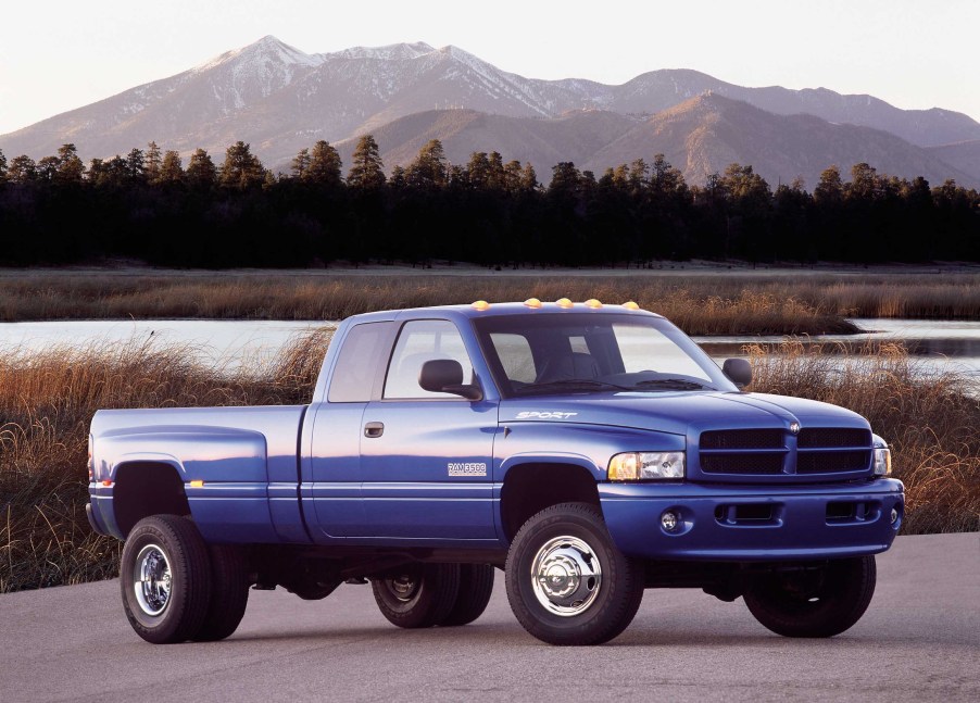 Blue 2001 Dodge Ram pickup truck with a 2nd Gen Cummins engine parked by a lake with mountains visible in the background.