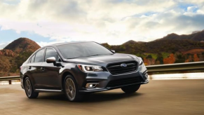 2018 Subaru Legacy driving on a road. shown in a list of the best used cars for gas mileage.