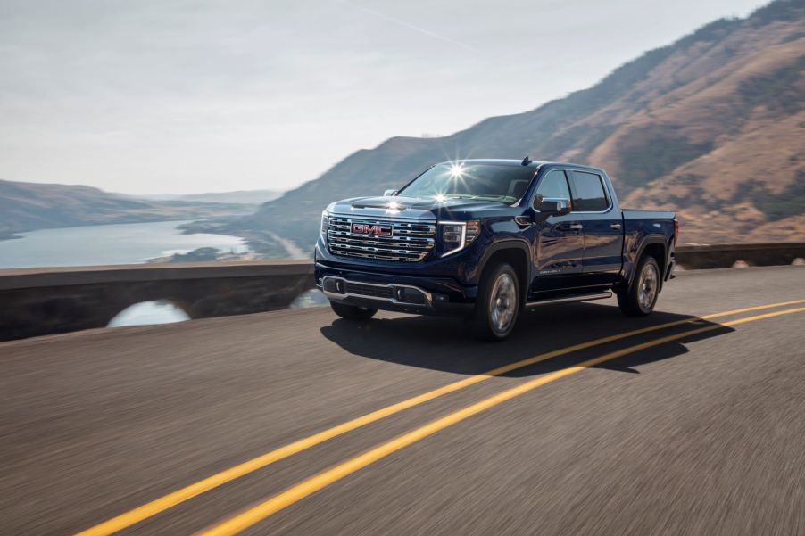 A 2022 GMC Sierra Denali full-size pickup truck model driving on a seaside highway