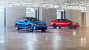 A Volkswagen Jetta and Jetta GLI on display in a warehouse.