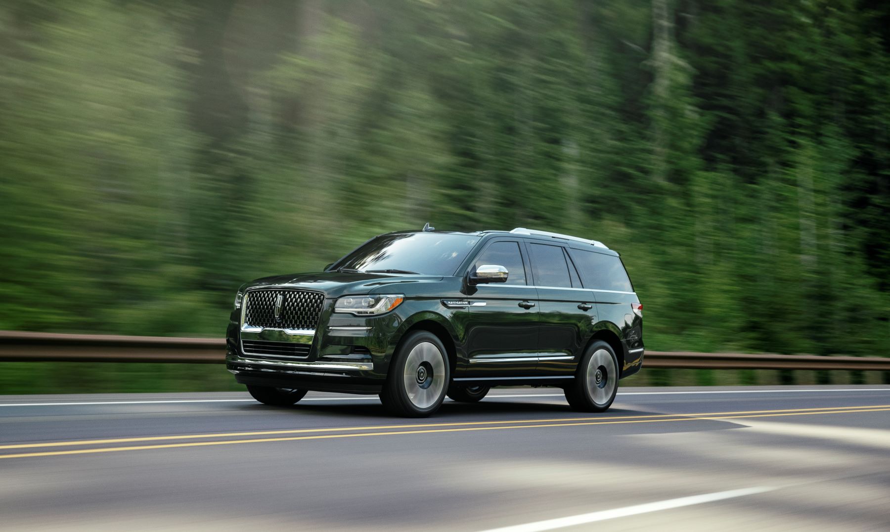 2022 Lincoln Navigator Manhattan Green Black Label full-size luxury SUV driving on a forest highway