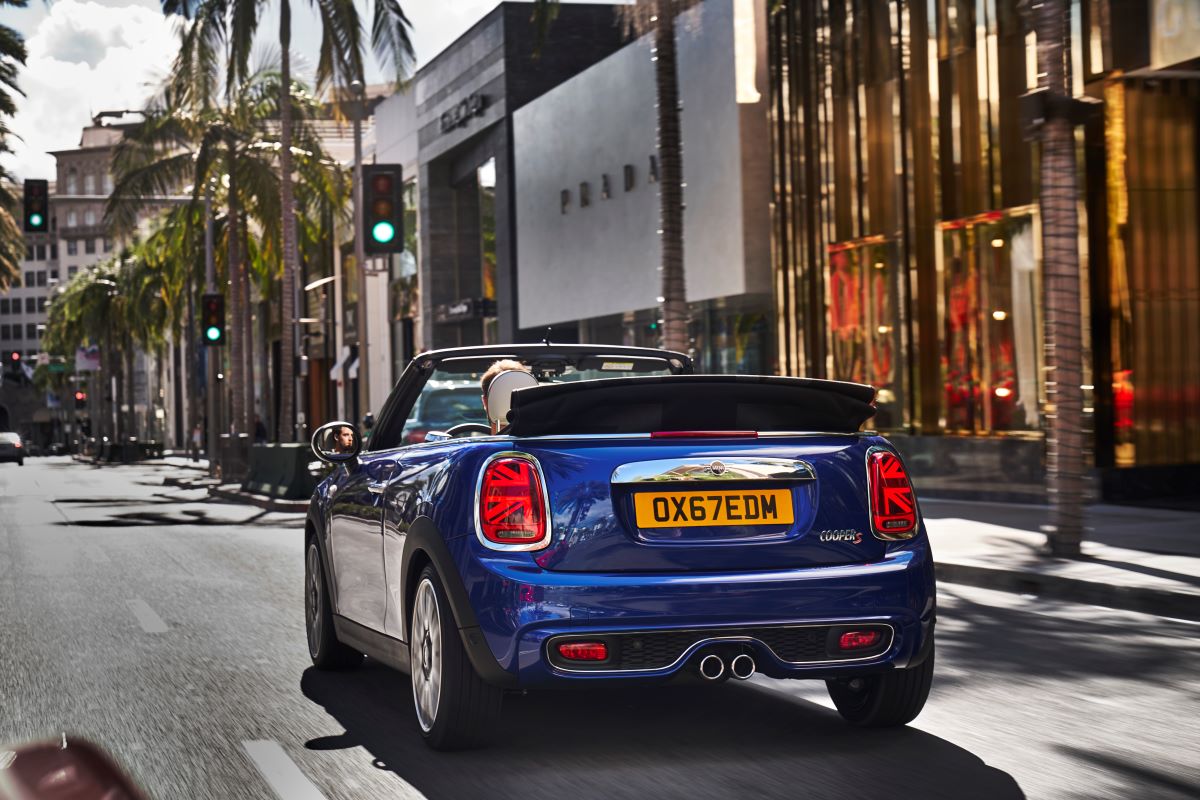 A blue 2023 MINI Cooper convertible drives through a city 