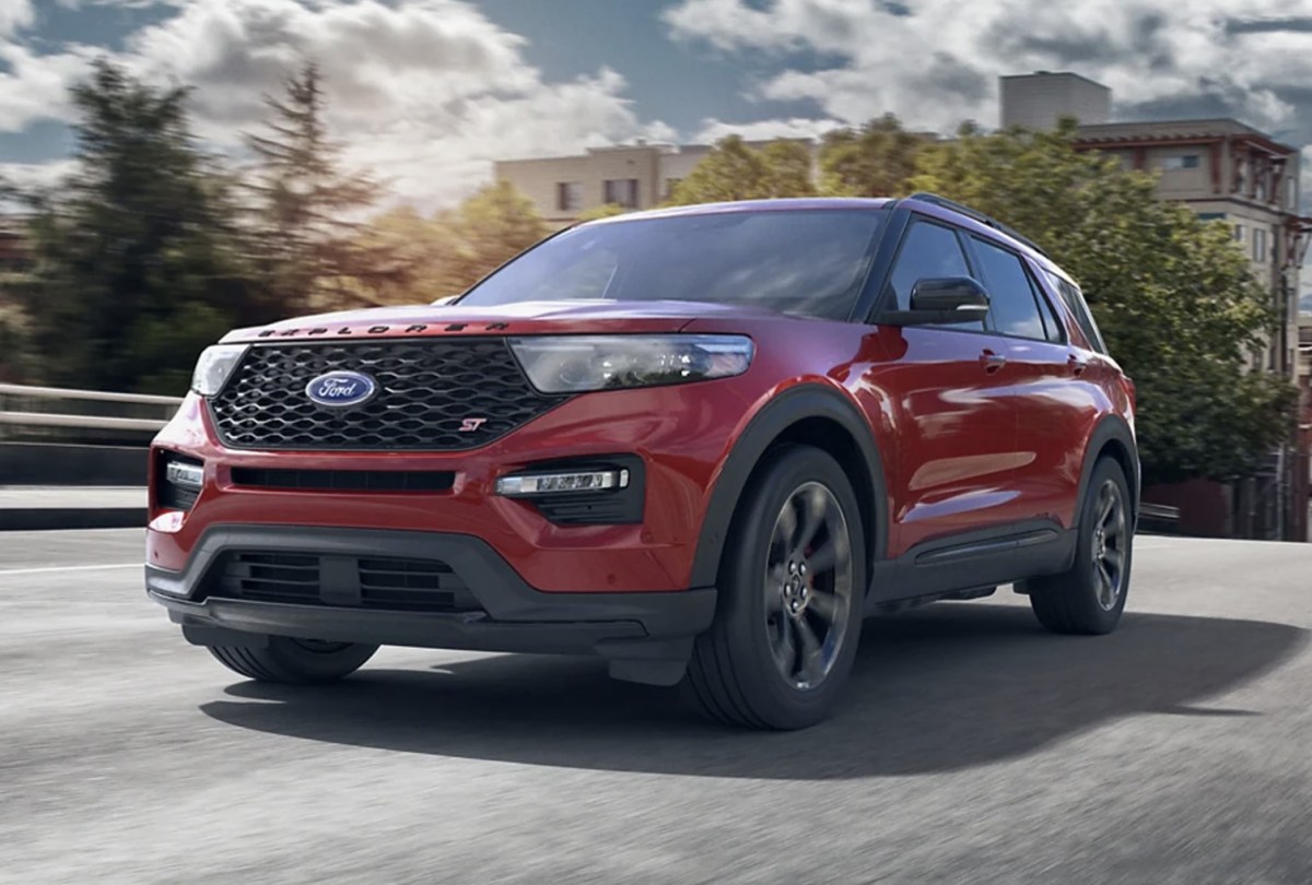 A red Ford Explorer driving down a city street.