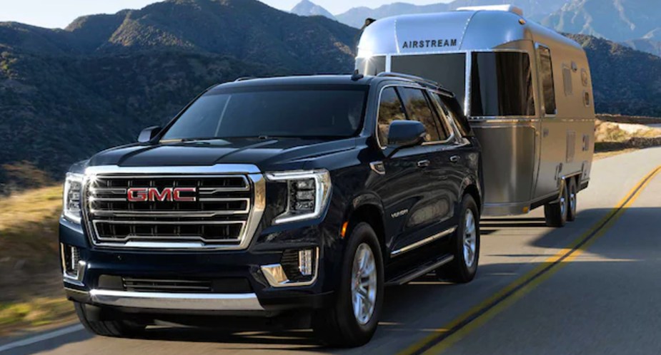 A black 2023 GMC Yukon XL is towing a trailer. 