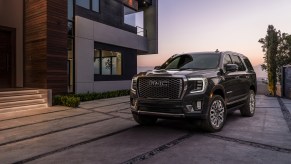 A blue 2023 GMC Yukon, which is one of the models most likely to last, parked in front of modern building.