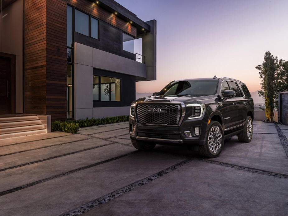 A blue 2023 GMC Yukon, which is one of the models most likely to last, parked in front of modern building.