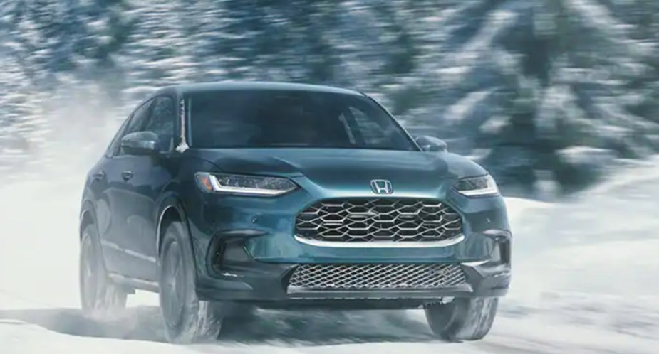 A green 2023 Honda HR-V subcompact SUV is driving through the snow. 