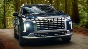 A blue 2023 Hyundai Palisade midsize SUV is driving off-road.