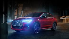 A red 2023 Infiniti QX55 is parked with headlights on at night. Is it underrated or overpriced?