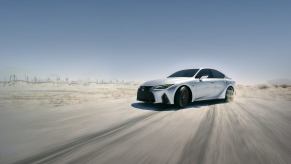 A 2023 Lexus IS driving on a dusty road.