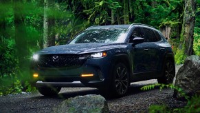 A blue 2023 Mazda CX-50 small SUV is driving off-road.