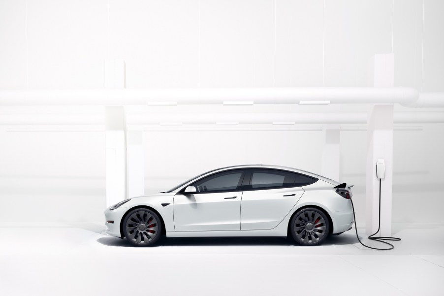 A Tesla Model 3 rental car charges in a white room.