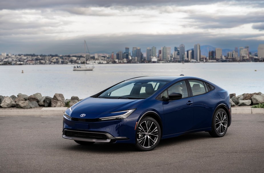 A new 2023 Toyota Prius Hybrid parks at a waterfront in a blue paint scheme. 